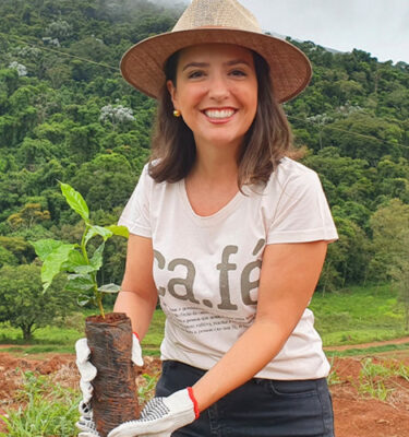 Carolina Coffee - owner smiling holding coffee sapling plant