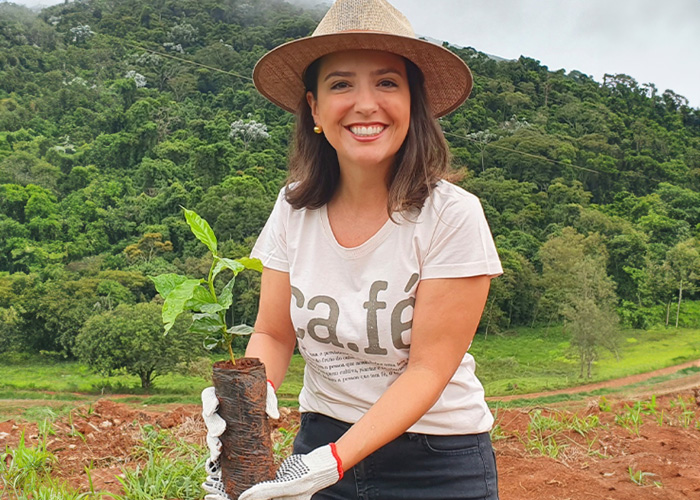 Carolina Coffee - owner smiling holding coffee sapling plant